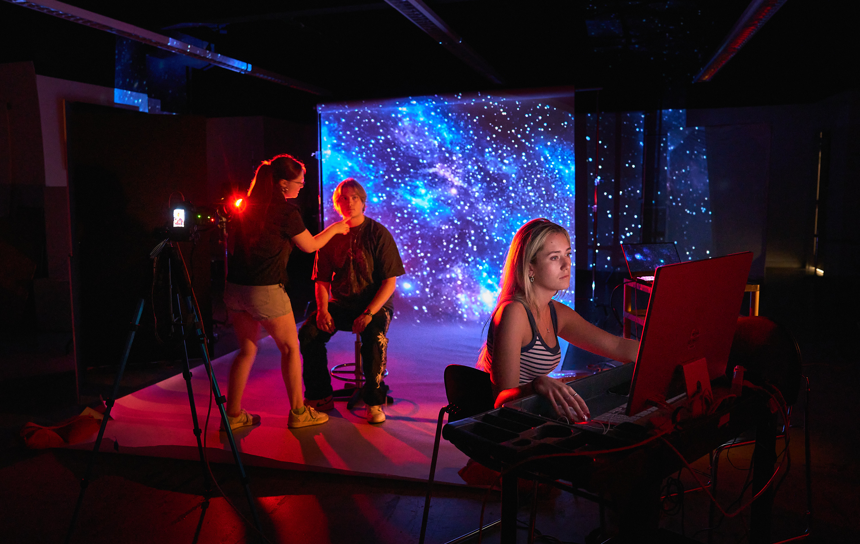 three students in photo studio with model in colored scarves