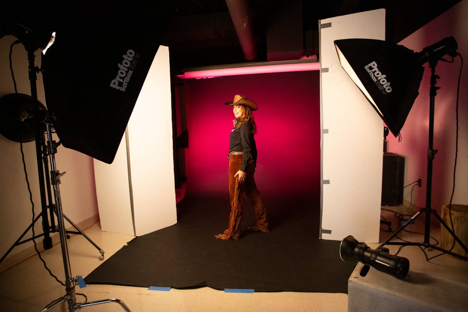 model in studio in western wear in front of red background