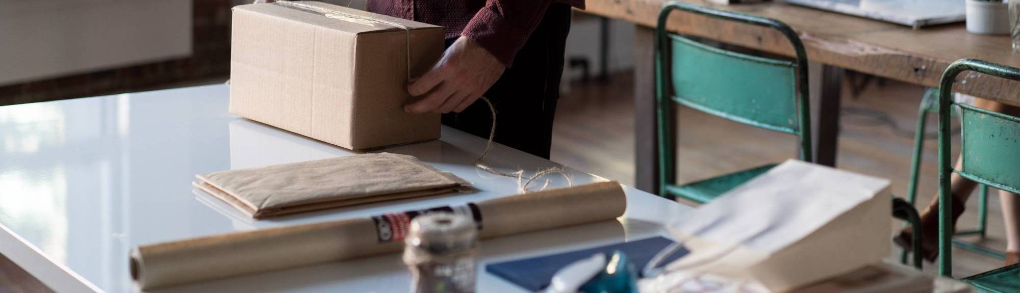 person packing a shipping box