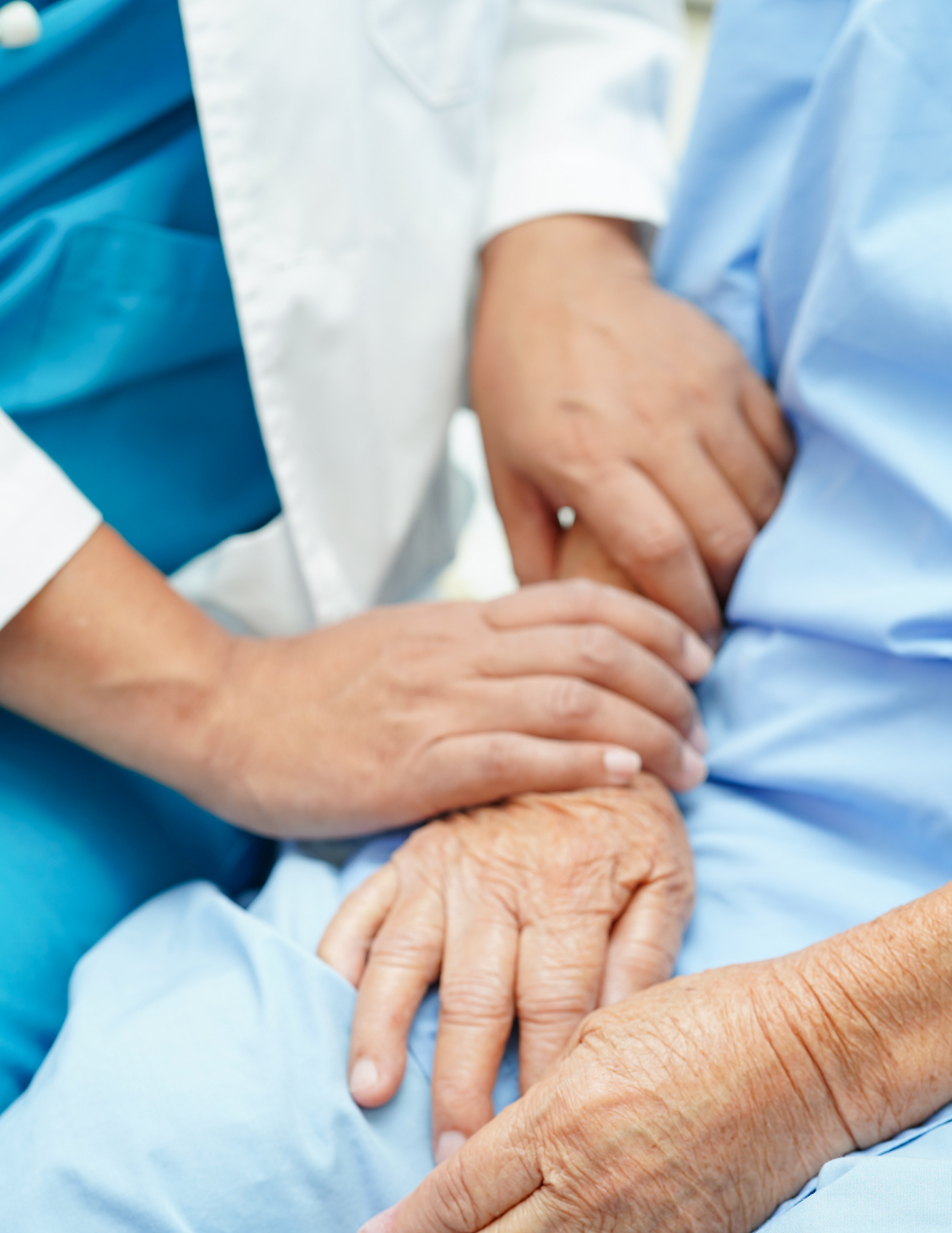 Close-up of two people, one in a white coat and one in blue, holding hands.