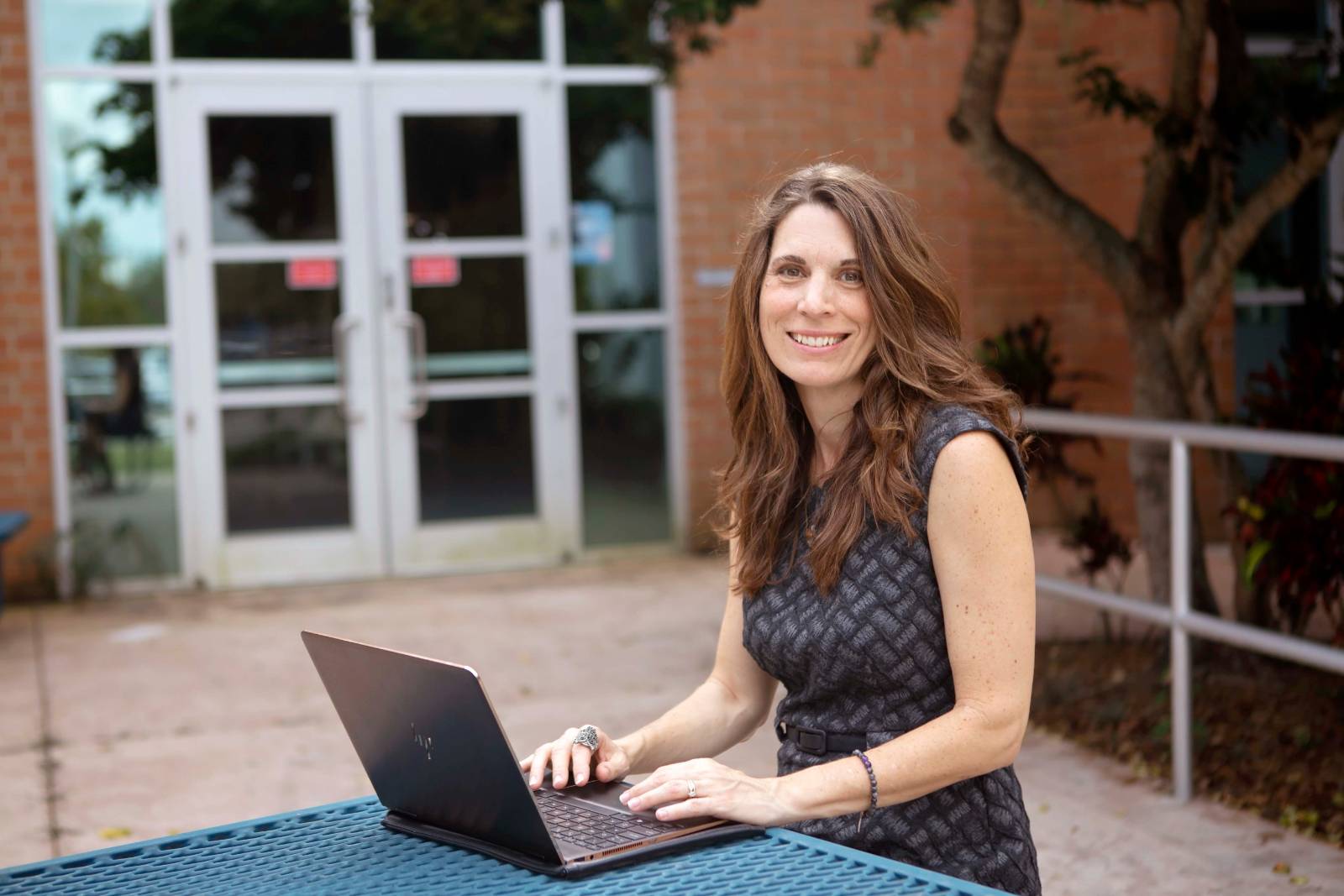 person outside at table with laptop