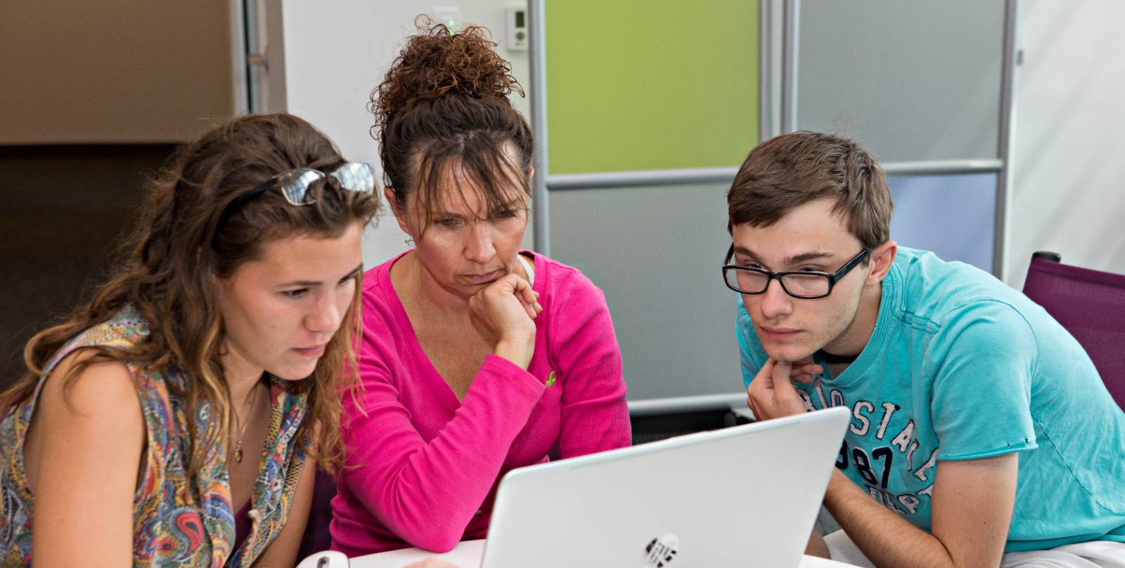 three students working together on a laptop