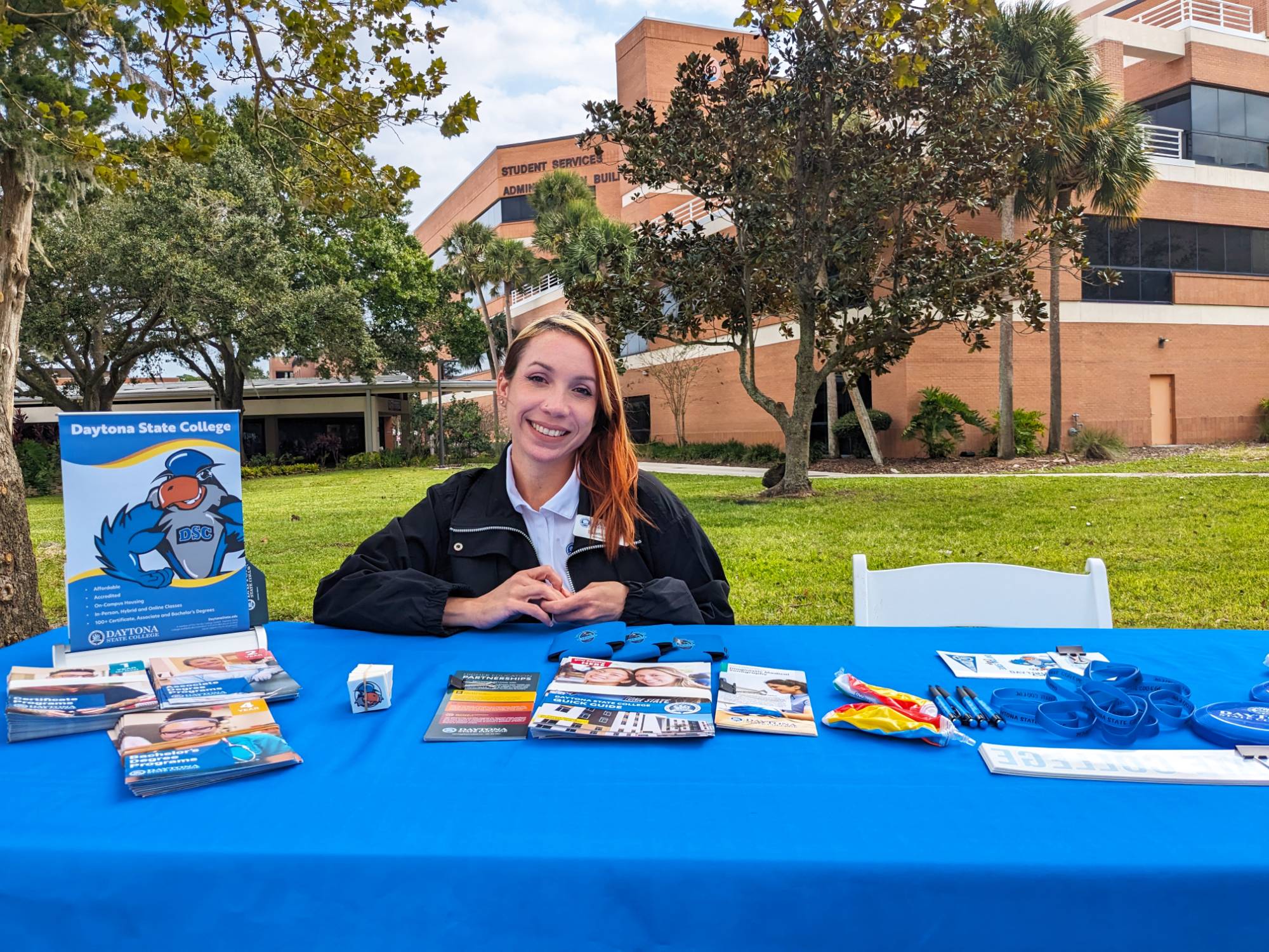 An employee staffing a table at a campus event. Out faculty and staff participate in a number of outreach activities on campus and in the community.