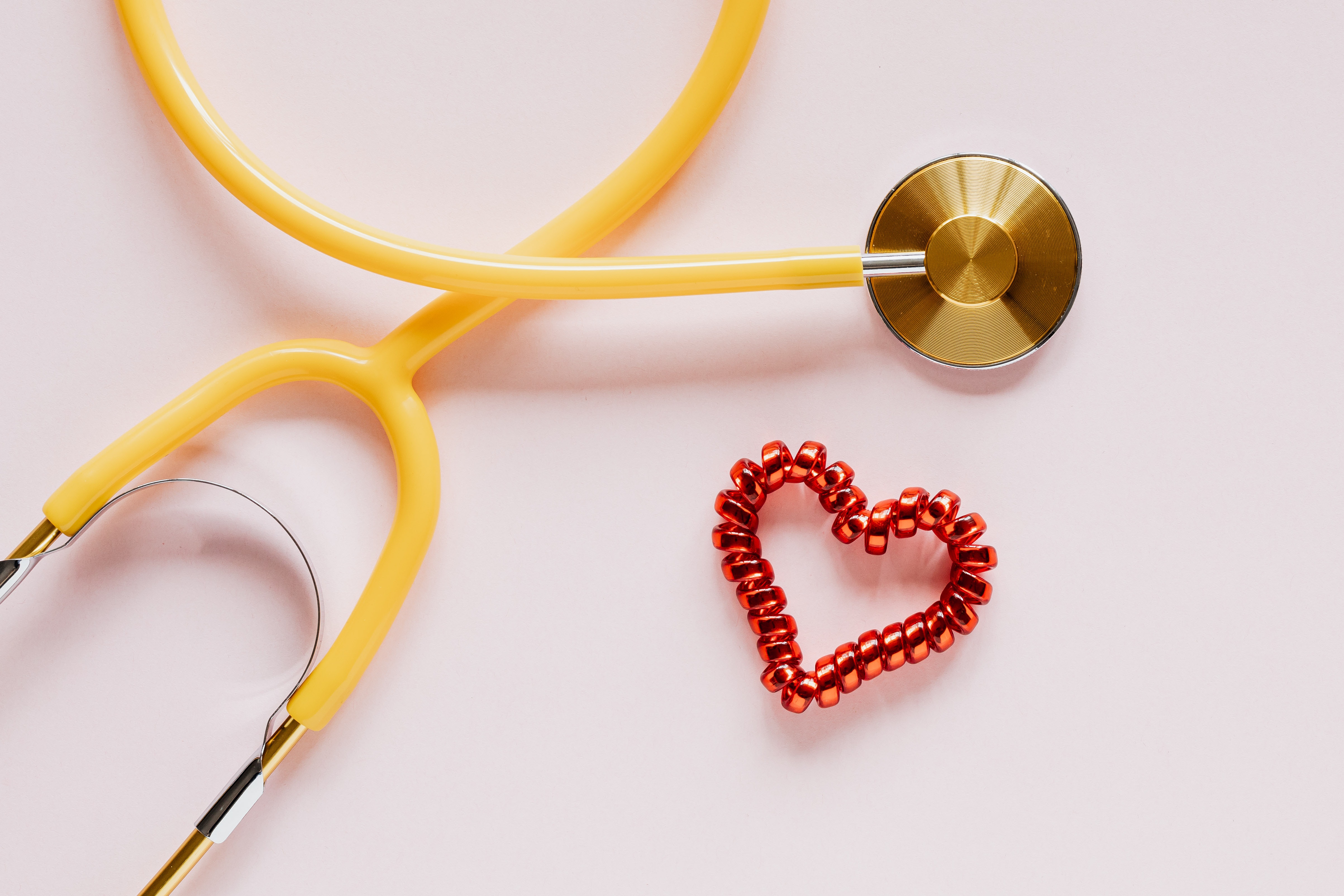 yellow stethoscope with red heart on white table top