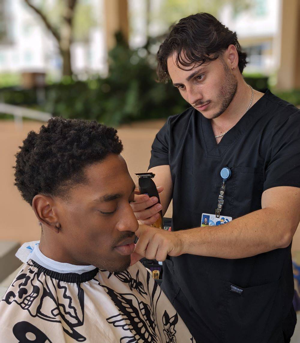 A student getting a haircut from another student in the Barbering program. 