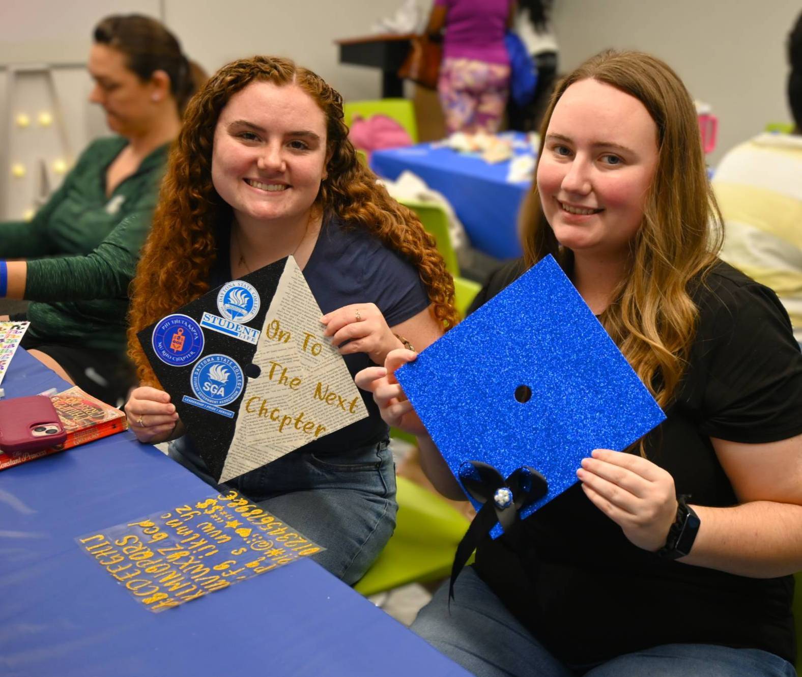 Two students decorate their caps for graduation. 