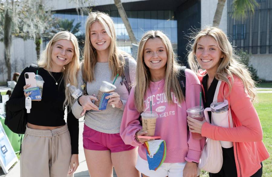 Two female students smiling at the camera standing in the courtyard in front of the student center