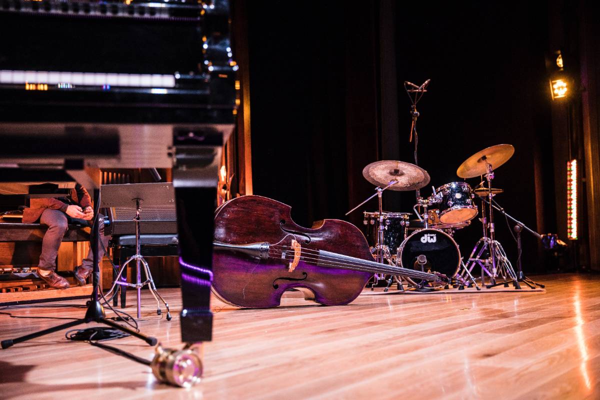 cello, piano, and drum kit on a stage