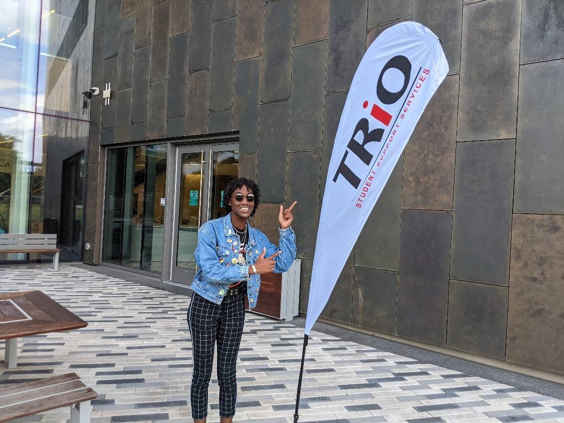 student pointing to TRiO flag