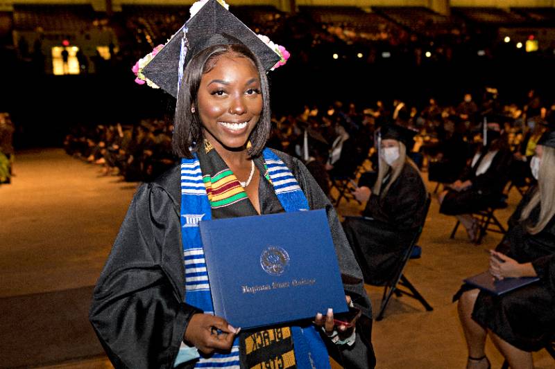 student a graduation ceremony holding their diploma 